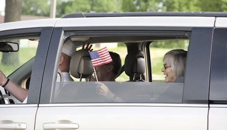 A woman waves a flag from a van during the Memorial Day parade. 