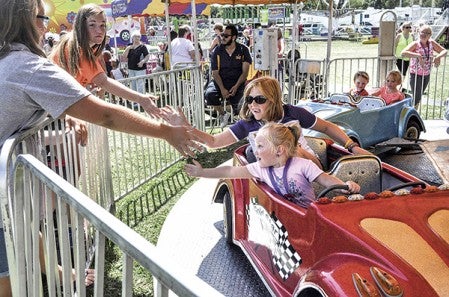 A couple of girls high five their friends as they go around on a ride at Daycare Day at the Mower County Fair last year. Herald file photo 
