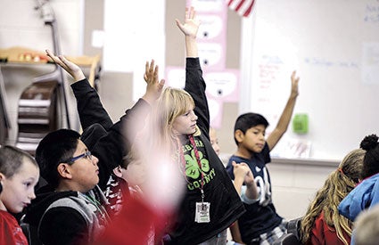 Students at I.J. Holton Intermediate School raise their hands to answer a question posed by members of the Mill City Quartet. 