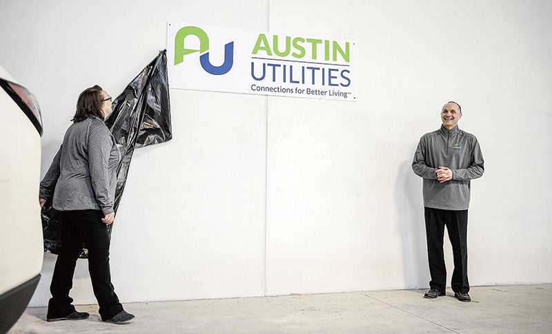 Austin Utilities General Manager Mark Nibaur and Kelly Lady unveil the new logo for Austin Utilities early this year. The logo features an intersecting A and U to represent Austin Utilities. The slant between letters is meant for an upward direction and organization that is forward thinking and upward moving. The blue color represents reliability, conservation and trust. The green means AU is committed to sustainability and efficient energy use. Herald file photo