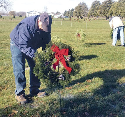 Volunteer Ron Osman tweaks a wreath placed on one of the graves.