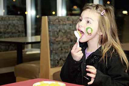 Maddie Wertish, 6, licks frosting from a spoon after decorating a cookie at Hy-Vee.