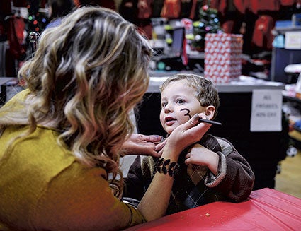 Louis Miller of Austin gets his face painted by Lizzy Wolterman at Games People Play last year night during Christmas in the Northwest. Louis turned three on the same day. Herald file photo