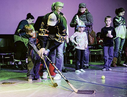 Four-year-old Oliver Theobald gets some help from the Austin Bruins Jason Koehn at Cornerstone.