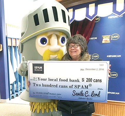 Bonnie Johnson, the 100,000th guest at the new Spam Museum, poses with Sir Can-A-Lot and a check for a donation of Spam to the local Salvation Army in Austin. Photo provided