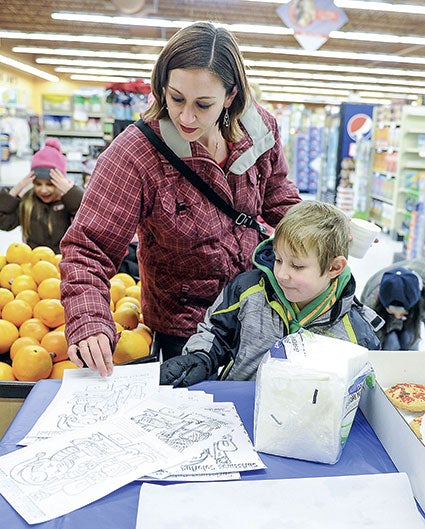  Jennie Stolzenberg and her son James, 5, pick up a coloring contest project at Jim’s MarketPlace Foods.