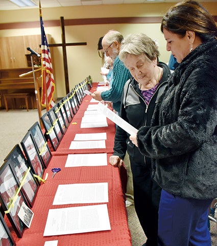 Ann Dolan, left, and her daughter, Meg Wagner, read John Dolan's biography as part of the Wall of Honor event at the Cedars of Austin on Wednesday. 