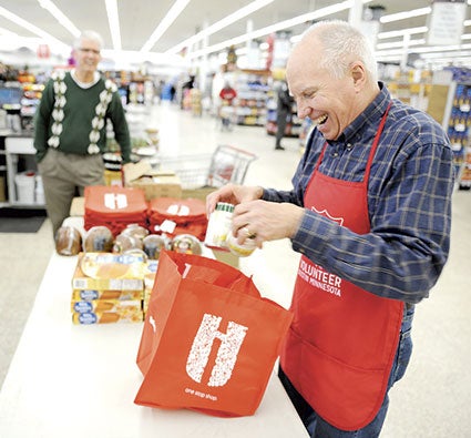 John Gray packages a bag with food as part of the Feed a Family distribution Wednesday at Hy-Vee.
