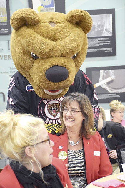 Austin Bruins mascot Bruiser the Bear tries to coax Rita Srock of The Eagles Club into bidding higher on tickets to the Paint the Rink Pink game during the Paint the Town Pink kickoff at The Hormel Institute Tuesday during Business After Hours. Jason Schoonover/jason.schoonover@austindailyherald.com