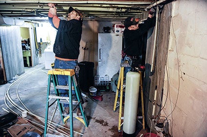 Todd Grundmeier, left, and Dennis Oquist hook a new water softener during the second Pay It Forward. Herald file photo