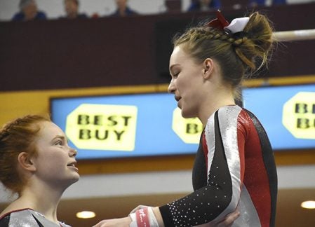 Austin’s Paige Raymond, right, and Morgan Raymond share a sisterly moment after Paige’s performance on the bars at the Minnesota State Class A Gymnastics Meet Friday at the Sports Pavillion at the University of Minnesota. Rocky Hulne/sports@austindailyherald.com